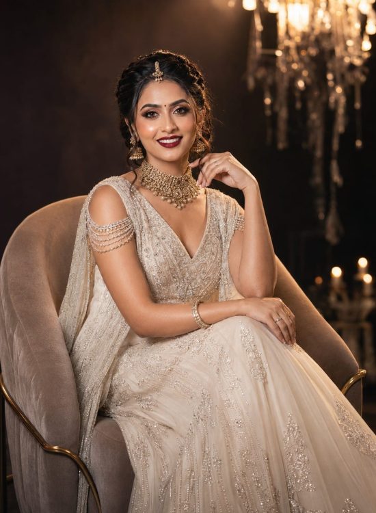 Stylish Indian bride sitting on luxury chair with flawless makeup